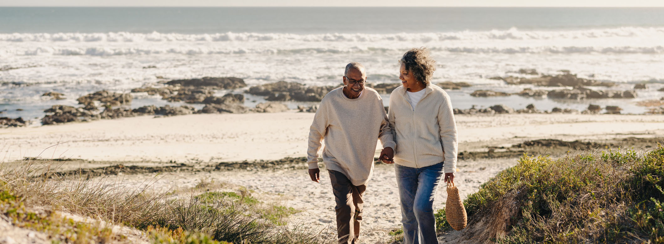 Smiling older couple walking on California beach illustrating retirement readiness and lifestyle-focused planning